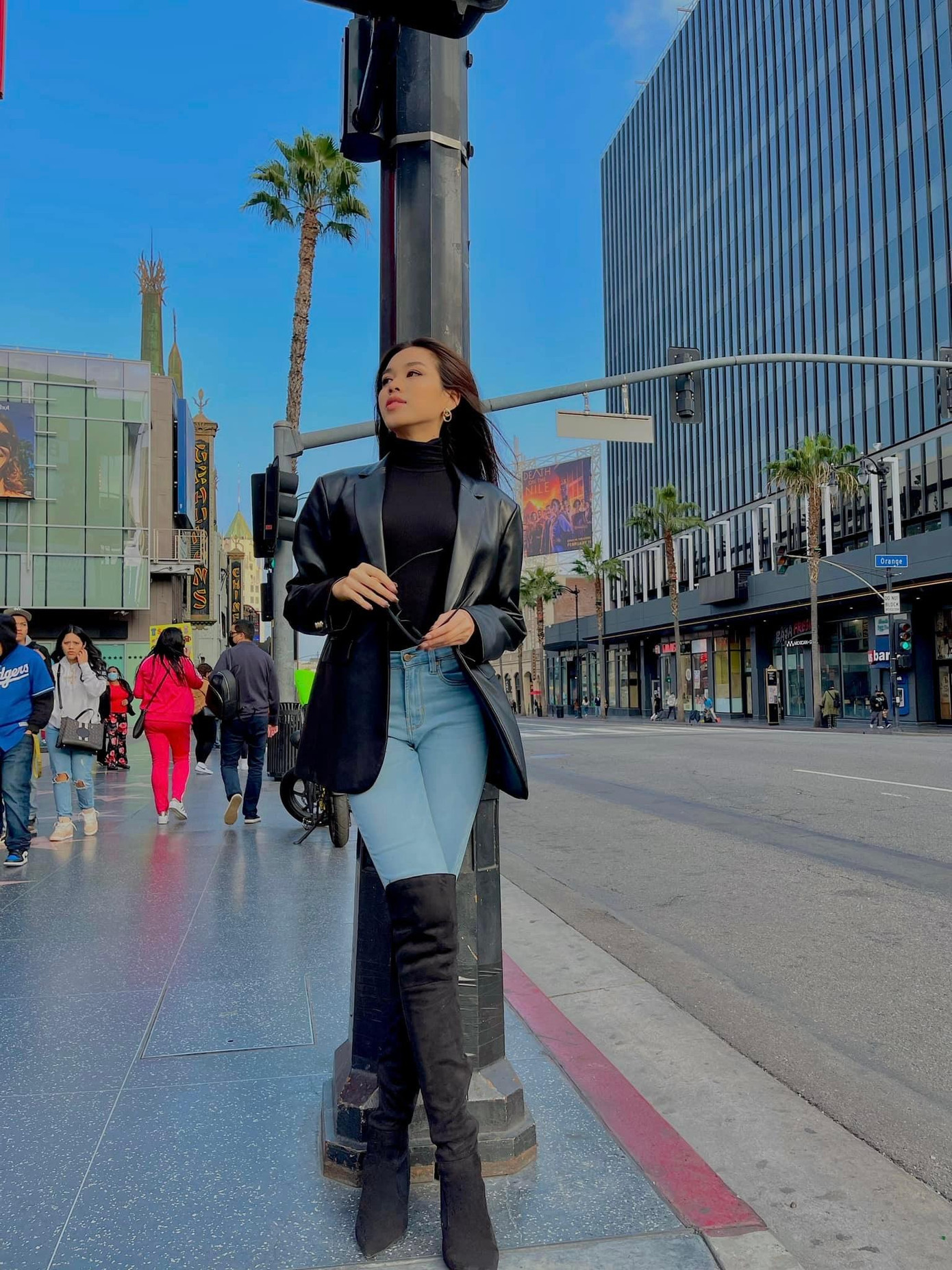 Người đẹp diện áo cổ lọ phối cùng quần jeans và đi boot cao quá đầu gối. Cô trang điểm nhẹ nhàng, để tóc thẳng và sử dụng phụ kiện kính mát sành điệu.