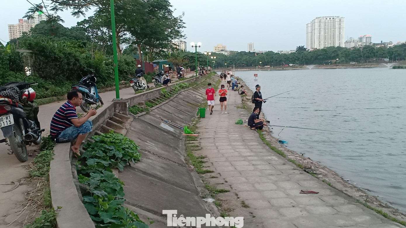 Ghi nhận của PV chiều 21/5, tại hồ Định Công (Hoàng Mai, Hà Nội), bên cạnh dòng người đông đúc chạy bộ, tập thể dục thì khu vực mép hồ, hàng chục cần thủ vẫn bình thản ngồi câu cá.