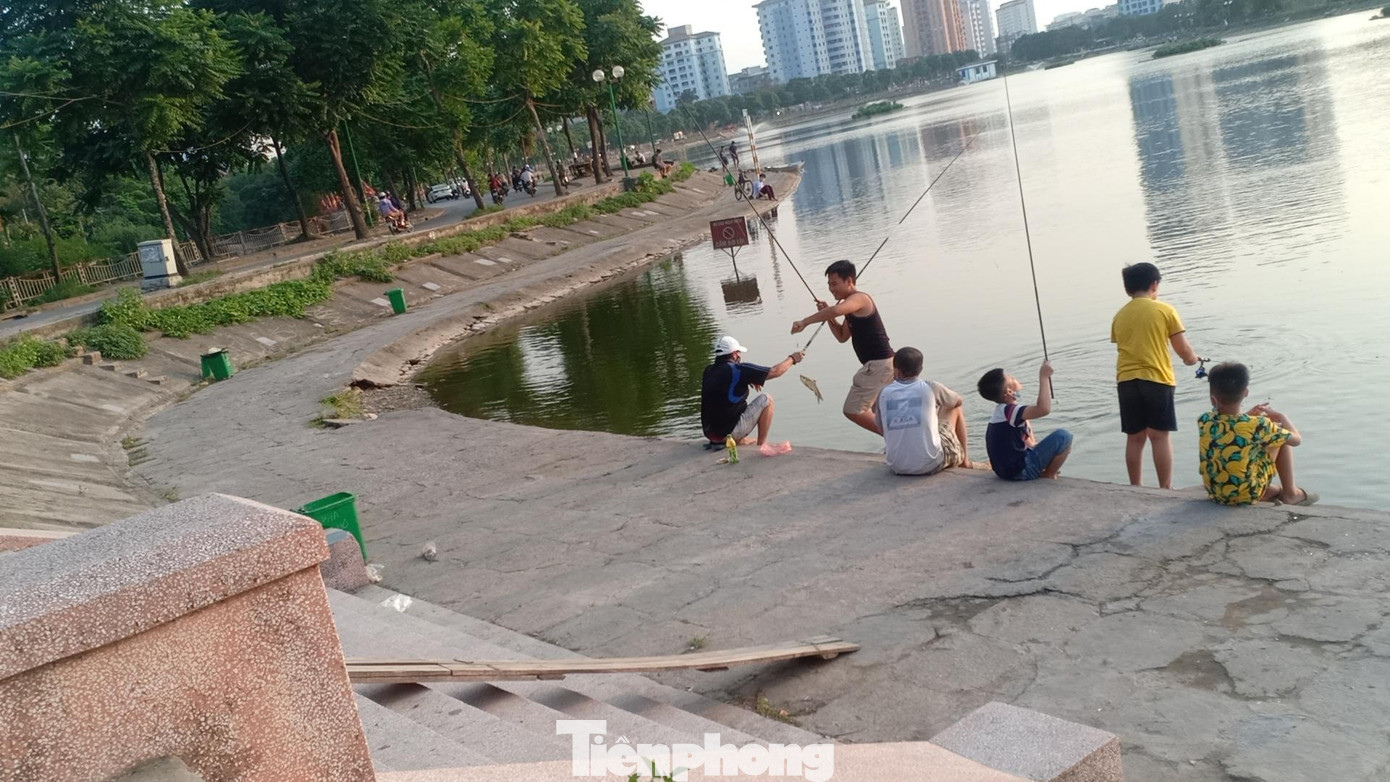 Ngoài ra, thú vui này còn thu hút nhiều học sinh, trẻ em. Nhiều người trong số đó không đeo khẩu trang. Ngoài việc người dân ngó lơ quy định phòng chống dịch của thành phố, nơi đây từ lâu đã biến thành địa bàn cho một số đối tượng tổ chức kinh doanh thu tiền dịch vụ câu cá cho những ai có nhu cầu. Một cần thủ tại đây cho hay, nếu muốn câu thì chỉ việc mang cần ra hồ, tự động sẽ có người đến phát vé, thu tiền. Còn không có thể đến đăng ký tại một quán nước mía ngay cạnh lối rẽ vào hồ. PV Tiền Phong đã tiếp cận với chủ quán này và được cho biết mức giá dao động từ 300-600 nghìn đồng/ca tùy từng loại cần. Theo quan sát, cứ khoảng 18 giờ trở đi, các đối tượng tự nhận là nhà hồ xuất hiện với chiếc xe máy cùng bộ đàm dắt bên mình. Những người này sẽ đi vòng quanh hồ để phát vé, thu tiền của người câu. Với mức giá và số lượng người câu đông đảo, “nhà hồ” có thể thu về tiền triệu mỗi ngày, thậm chí lên cả chục triệu từ việc thu phí chưa kể việc cho thuê đồ câu, phụ kiện câu, dịch vụ kèm theo… Trước đó (31/12/2020), báo Tiền Phong cũng đã từng có bài viết phản ánh về tình trạng này. Nhưng đến nay có thể thấy, hoạt động câu cá dịch vụ vẫn diễn ra ngang nhiên bất chấp pháp luật. Việc tổ chức thả cá, câu cá tại hồ Định Công là không đúng quy định, tiềm ẩn nguy cơ gây mất an ninh trật tự, vệ sinh môi trường, văn minh đô thị và ảnh hưởng nghiêm trọng đến nguồn nước.