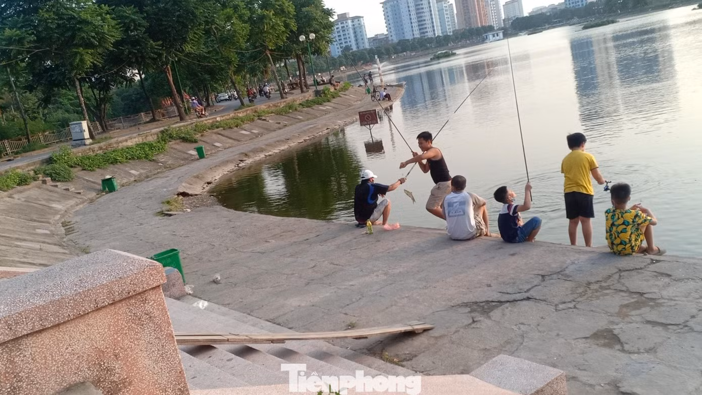 Ngoài ra, thú vui này còn thu hút nhiều học sinh, trẻ em. Nhiều người trong số đó không đeo khẩu trang. Ngoài việc người dân ngó lơ quy định phòng chống dịch của thành phố, nơi đây từ lâu đã biến thành địa bàn cho một số đối tượng tổ chức kinh doanh thu tiền dịch vụ câu cá cho những ai có nhu cầu. Một cần thủ tại đây cho hay, nếu muốn câu thì chỉ việc mang cần ra hồ, tự động sẽ có người đến phát vé, thu tiền. Còn không có thể đến đăng ký tại một quán nước mía ngay cạnh lối rẽ vào hồ. PV Tiền Phong đã tiếp cận với chủ quán này và được cho biết mức giá dao động từ 300-600 nghìn đồng/ca tùy từng loại cần. Theo quan sát, cứ khoảng 18 giờ trở đi, các đối tượng tự nhận là nhà hồ xuất hiện với chiếc xe máy cùng bộ đàm dắt bên mình. Những người này sẽ đi vòng quanh hồ để phát vé, thu tiền của người câu. Với mức giá và số lượng người câu đông đảo, “nhà hồ” có thể thu về tiền triệu mỗi ngày, thậm chí lên cả chục triệu từ việc thu phí chưa kể việc cho thuê đồ câu, phụ kiện câu, dịch vụ kèm theo… Trước đó (31/12/2020), báo Tiền Phong cũng đã từng có bài viết phản ánh về tình trạng này. Nhưng đến nay có thể thấy, hoạt động câu cá dịch vụ vẫn diễn ra ngang nhiên bất chấp pháp luật. Việc tổ chức thả cá, câu cá tại hồ Định Công là không đúng quy định, tiềm ẩn nguy cơ gây mất an ninh trật tự, vệ sinh môi trường, văn minh đô thị và ảnh hưởng nghiêm trọng đến nguồn nước.