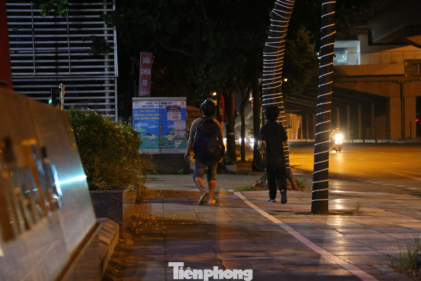 Anh Sơn cho biết, hàng ngày hai bố con anh đi lang thang khắp nơi để xin cơm từ thiện. Buổi tối, khi đã thấm mệt, hai người chọn một vỉa hè hay một gầm cầu nào đó làm nơi nghỉ tạm. Trong ảnh là Đinh Quang Đạt quê Mai Châu, Hòa Bình. Đạt đang ăn ở tại tại khu vực gầm cầu vành đai 3 dọc đường Khuất Duy Tiến (đoạn qua hồ điều hòa Nhân Chính). Tối đến, Đạt lại rời nơi trú ngụ của mình để đi nhặt phế liệu. “Em sợ con virus này lắm, nên đi đêm ít người nên chắc sẽ bớt bị ảnh hưởng hơn. Với lại, ban ngày nóng bức cộng em lo không làm ăn được gì mấy. Không biết bao giờ mới đủ tiền bắt xe về quê”, thanh niên người dân tộc Thái cười nói. Đạt cho biết, nhà nghèo, mẹ bị bệnh tật liên miên, không lao động nặng được. Đạt bỏ học sớm để đi làm phụ hồ kiếm tiền nuôi mẹ. Mới đây, em làm cốt pha cho một nhà chủ ở tỉnh Hưng Yên. Do dịch bệnh, công việc không được thuận lợi, Đạt tính đi về nhà ở huyện Mai Châu (Hòa Bình) nhưng do không thông thuộc đường, Đạt lạc lên Hà Nội đúng vào thời điểm giãn cách xã hội. Đạt cho biết, lúc mới lên Hà Nội, em ở trọ cùng một người bạn mới quen. Tuy nhiên, mới ở một đêm, hôm sau ngủ dậy cả ví tiền, điện thoại, quần áo, giấy xét nghiệm COVID-19 bị lấy cắp mất cả. Đạt đành phải ra gầm cầu ở và hàng đêm đi nhặt phế liệu để hôm sau bán lấy tiền mua mỳ tôm sống qua ngày. Dưới gầm cầu đường vành đài 3 dọc quốc lộ 1A (đoạn gần bến xe Nước Ngầm) là nơi trú ngụ của ba người đàn ông khác đến từ Nam Định, Điện Biên và Nghệ An. Hàng ngày, họ trông chờ vào những suất cơm từ thiện, nếu không thì nhai mỳ tôm sống. Mọi sinh hoạt cá nhân, sạc pin điện thoại, họ nhờ các nhà dân gần đó trợ giúp. Anh Lô Văn Cà Huệ (quê huyện Quế Phong, tỉnh Nghệ An) tâm sự, anh lên Hà Nội tìm việc từ đợt Tết 2021. Công việc cơ khí dân dụng bên quận Long Biên của anh vẫn suôn sẻ đến khi Hà Nội thực hiện những biện pháp thắt chặt để phòng chống dịch. “Tôi đi làm lương được 5 triệu đồng/tháng. Đóng tiền trọ 1 tháng hết khoảng 1,2 triệu đồng, giờ mất việc tôi ra đây với anh em cho tiết kiệm tiền trọ”, thanh niên người dân tộc Thái chia sẻ. Trình duyệt của bạn không hỗ trợ hiển thị video. Clip: Đinh Quang Đạt kể về cuộc sống ngày ở gầm cầu, đêm nhặt rác của mình