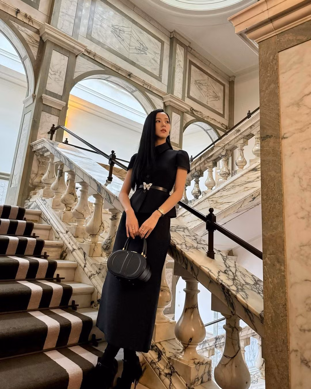 Jisoo mặc áo khoác Dior Fitted Short Sleeve, váy suông dài vừa phải, thắt lưng Métamorphose, dép cao gót Mlle, hoa tai Cartier Trinity và đồng hồ Cartier Crash trong buổi nhận Huân chương MBE danh dự từ Vua Charles tại Cung điện Buckingham, Anh.