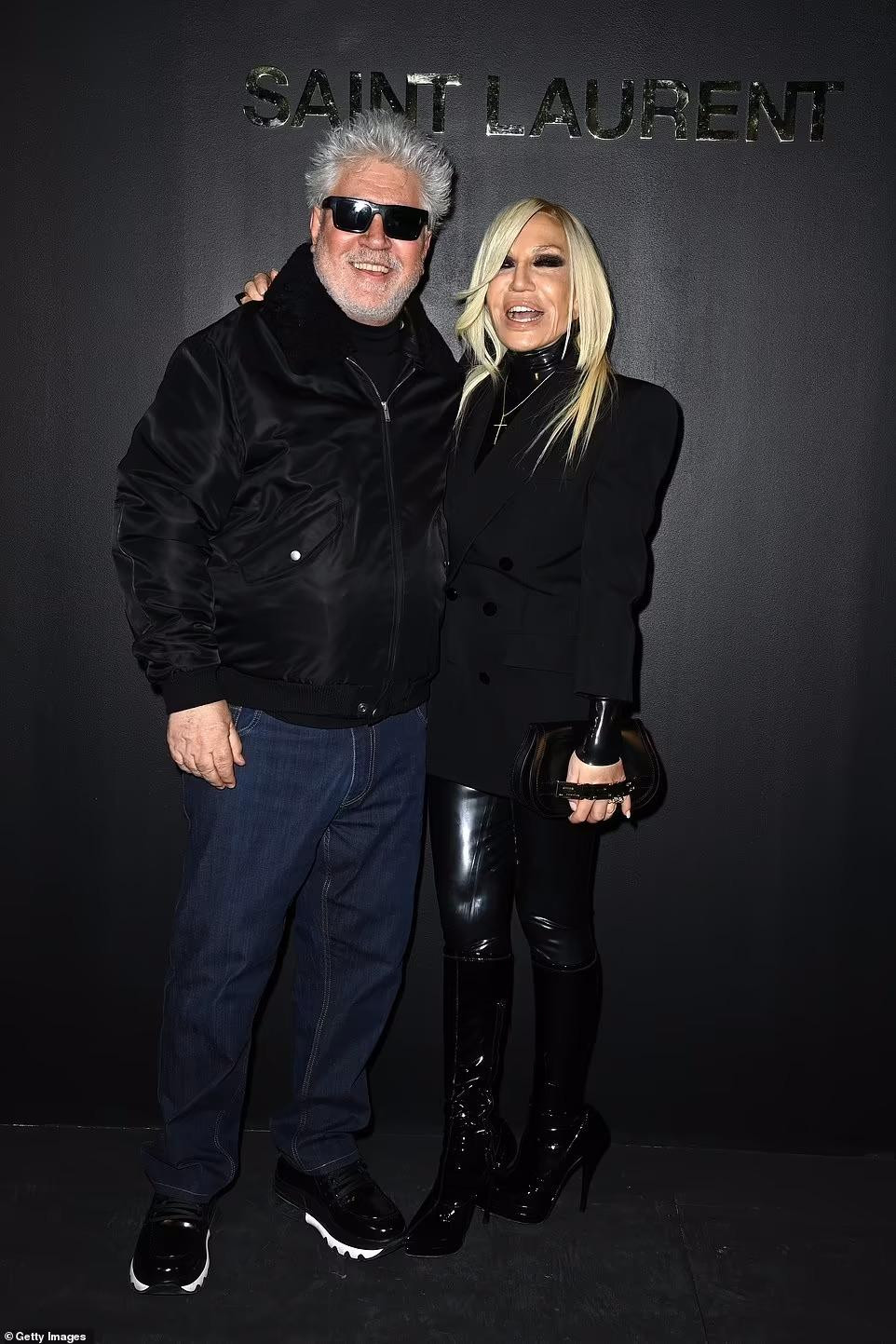 Đạo diễn Pedro Almodovar và nhà thiết kế thời trang Donatella Versace khoác vai thân thiết trên thảm đen.