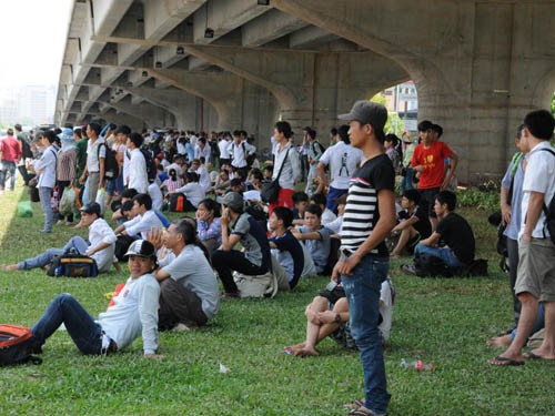 Nhiều phụ huynh, sĩ tử phải ngồi ngoài dải phân cách, bên dưới cầu vượt tránh nắng, chờ đến chi