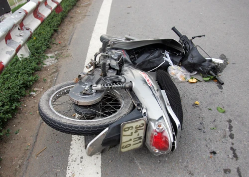 Xe máy bị xe tải kéo lê 20 m, văng vào lề. Ảnh: An Nhơn (VnExpress)