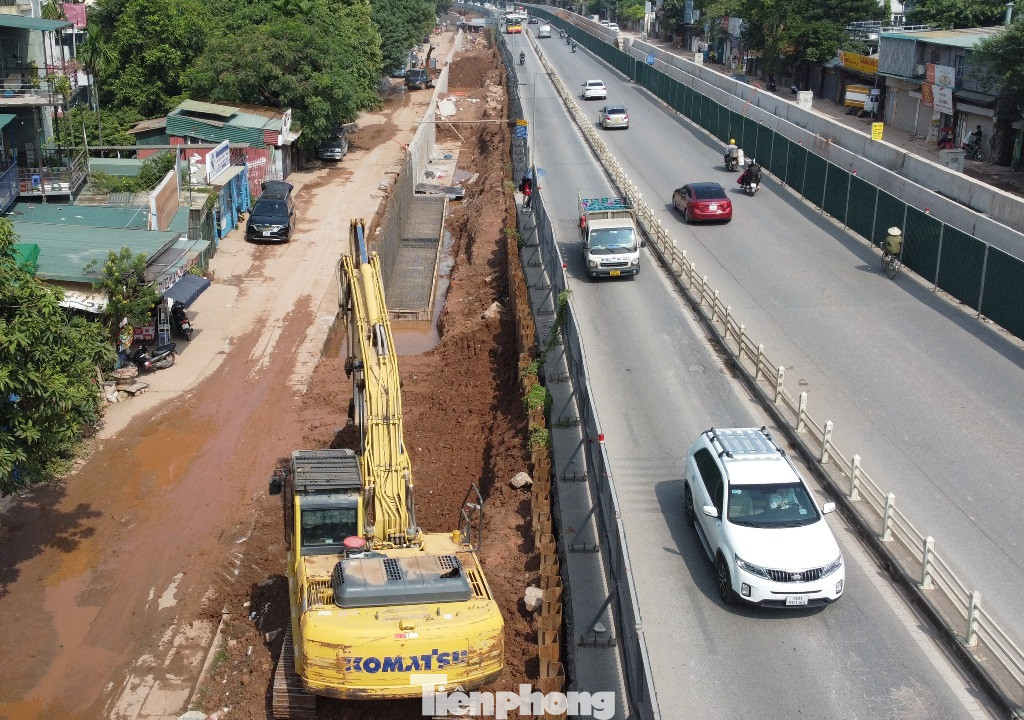 Máy móc thi công đang hạ mặt đê để mở rộng đường Âu Cơ - Nghi Tàm.