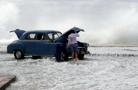 Một chiếc Plymouth bị ngập nước khi sóng biển tràn qua tường chắn tại Malecon, Havana vào năm 2003