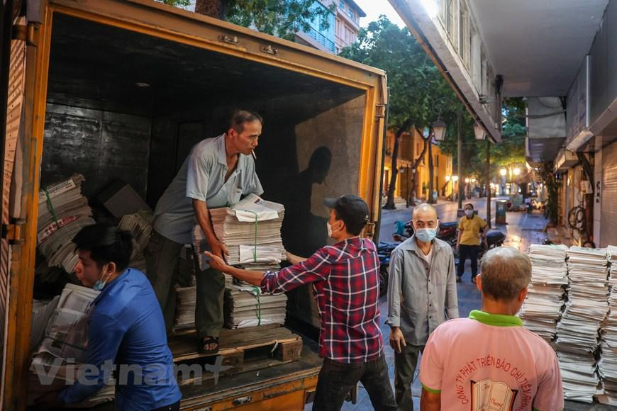 Hằng ngày, cứ vào khoảng 4 giờ 30, trên vỉa hè con phố Đinh Lễ (Quận Hoàn Kiếm) lại rộn ràng cảnh hàng chục người phân loại, giao báo. (Ảnh: Minh Sơn/Vietnam+)