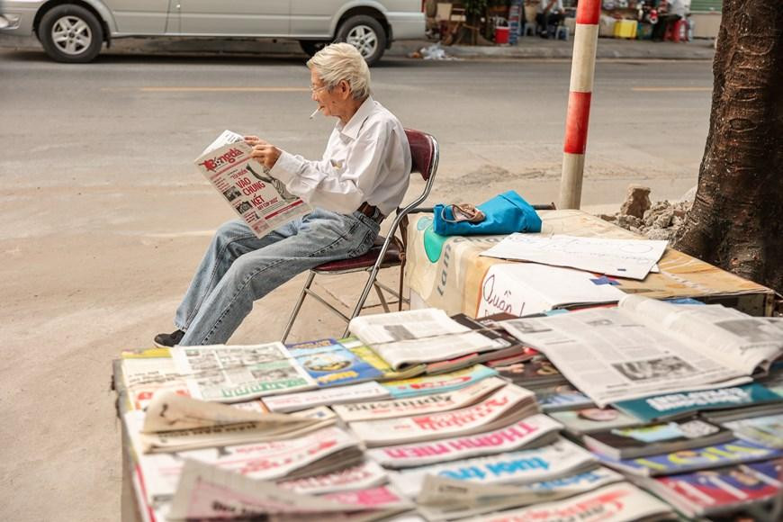 Thời buổi công nghệ thông tin phát triển, nhu cầu mua báo giấy ngày càng giảm. Những sạp báo in trên vỉa hè Hà Nội ngày một thưa thớt dần. Chính vì thế tìm kiếm được một sạp báo hay một người đọc báo không hề dễ dàng. (Ảnh: Minh Sơn/Vietnam+)