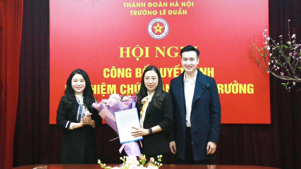 Bí thư Thành Đoàn Hà Nội Chu Hồng Minh và anh Đào Đức Việt - Phó Bí thư Thành Đoàn, Chủ tịch Hội đồng Đội Thành phố Hà Nội trao quyết định, tặng hoa chúc mừng tân Hiệu trưởng Trường Lê Duẩn - Nguyễn Thị Mai Hương. Ảnh: Hoàng Bảo