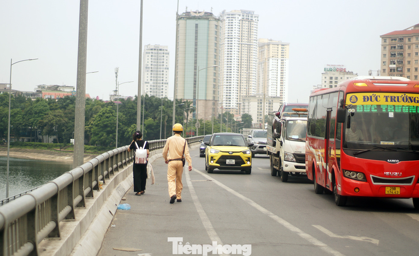 Nữ sinh đứng đợi xe trên đường Vành đai 3 trên cao được tổ công tác nhắc nhở, hỗ trợ di chuyển xuống phía dưới đảm bảo an toàn.