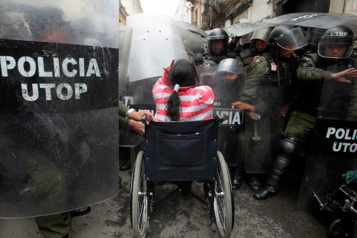 Một phụ nữ khuyết tật ngồi xe lăn trong cuộc đụng độ với cảnh sát chống bạo động ở La Paz, Bolivia. 