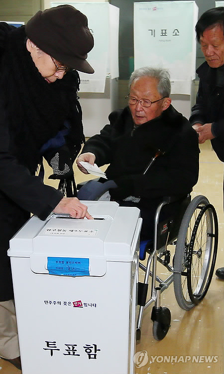 Một cử tri người cao tuổi đi xe lăn tới bỏ phiếu bầu cử 