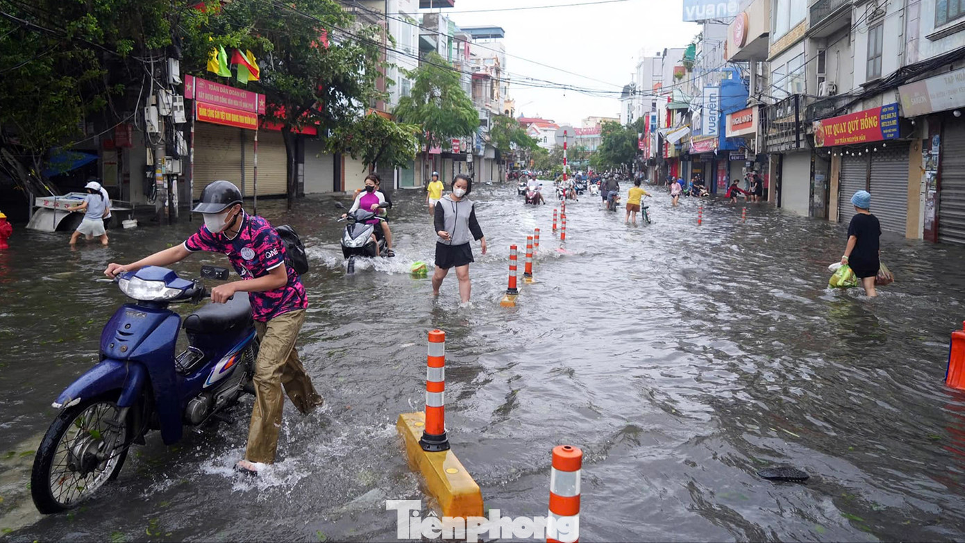 Trong khi trên phố Trần Nguyên Hãn ngập quãng đường dài, lực lượng chức năng dùng cảnh báo phản quang phân luồng và cảnh báo khu vực ngập sâu, có hố ga thoát nước.