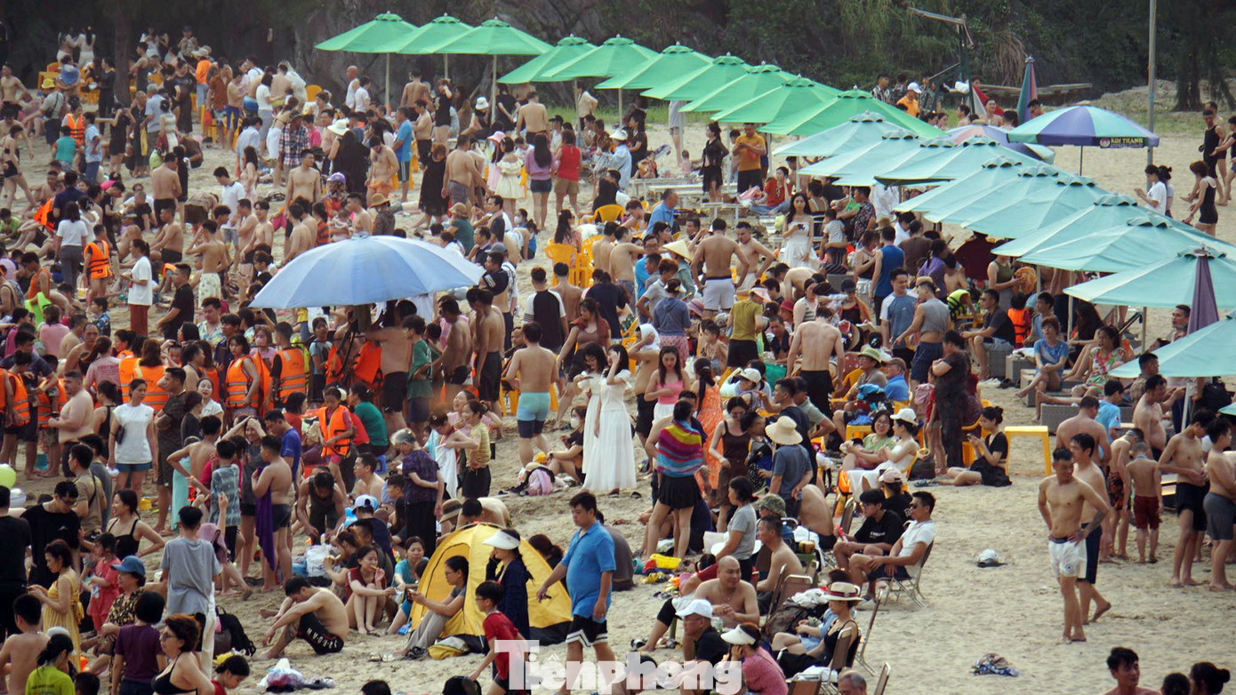 Trên bờ cát bãi tắm Tùng Thu, du khách thuê ô che nắng và ghế ngồi giữ chỗ để đồ ăn thức uống và đồ cá nhân. Bãi cát dài khoảng 400-500 m ken đặc khách du lịch.