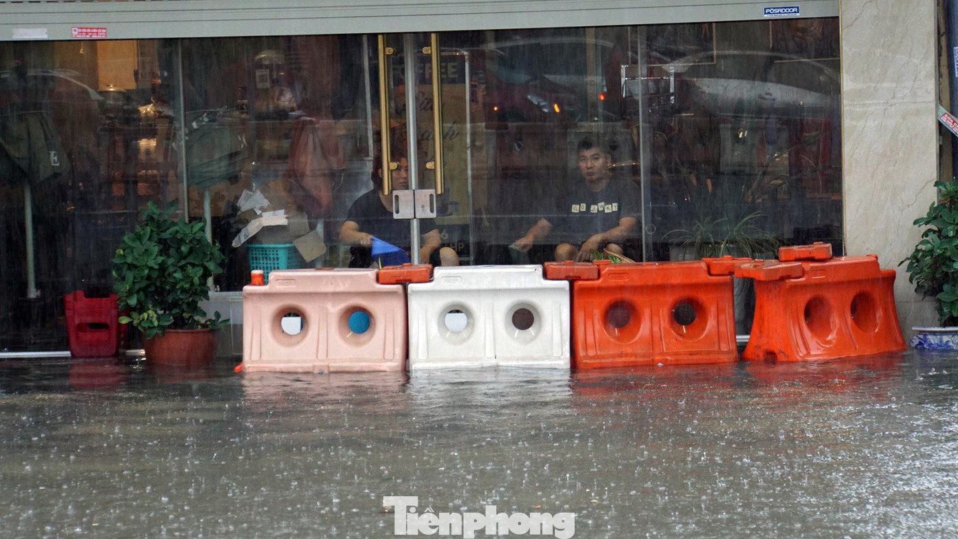 Chủ một cửa hàng cà phê trên phố Lạch Tray dùng dải phân cách bị đánh dạt che chắn sóng nước tràn vào nhà. Đồng thời, thay nhau dùng gáo tát nước ra khỏi cửa hàng. Chủ một cửa hàng cà phê trên phố Lạch Tray dùng dải phân cách bị đánh dạt che chắn sóng nước tràn vào nhà. Đồng thời, thay nhau dùng gáo tát nước ra khỏi cửa hàng.