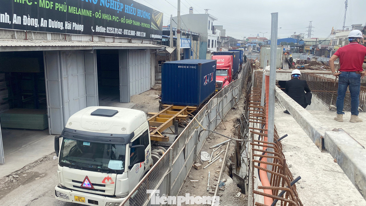 Xe tải, container nối đuôi nhau di chuyển trên QL, đoạn qua dự án đang thi công vào buổi trưa.