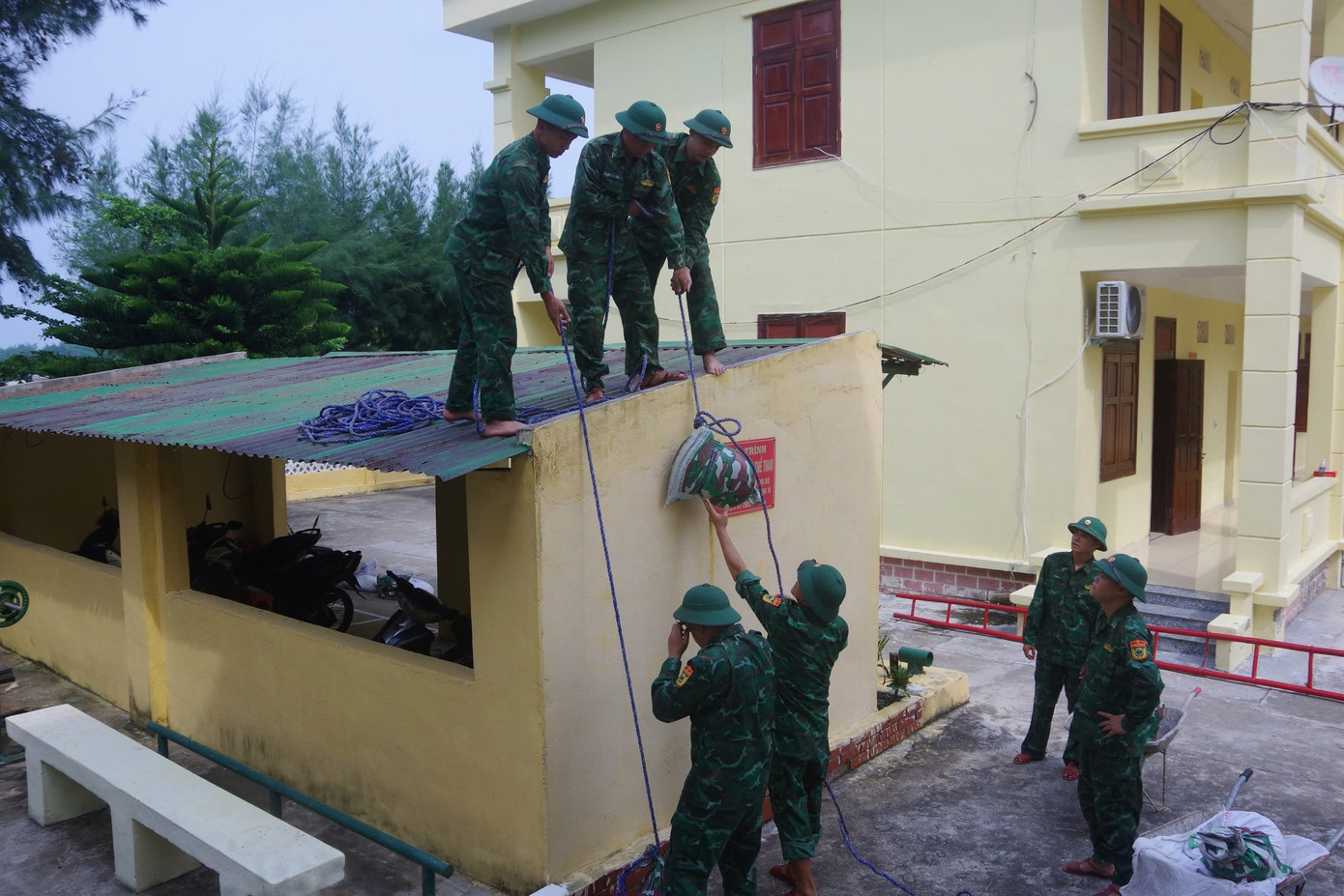 Hình ảnh bộ đội biên phòng chằng buộc, gia cố mái nhà công sở nhằm giảm thiểu thiệt hại về tài sản.