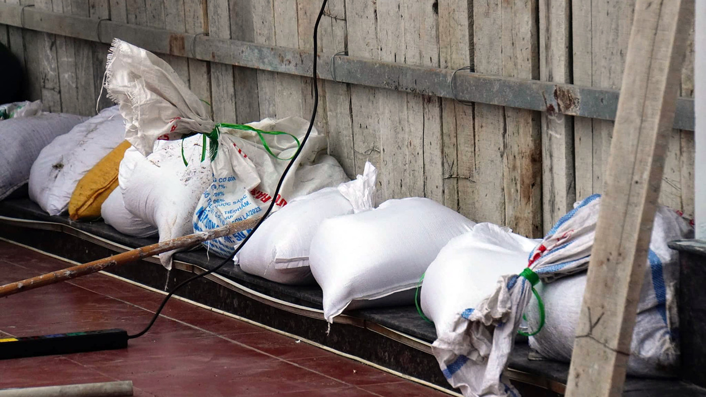 Bao cát đắp kín chân ván gỗ che chắn cho cửa kính và hạn chế sóng biển đánh vào gây thiệt hại về tài sản.