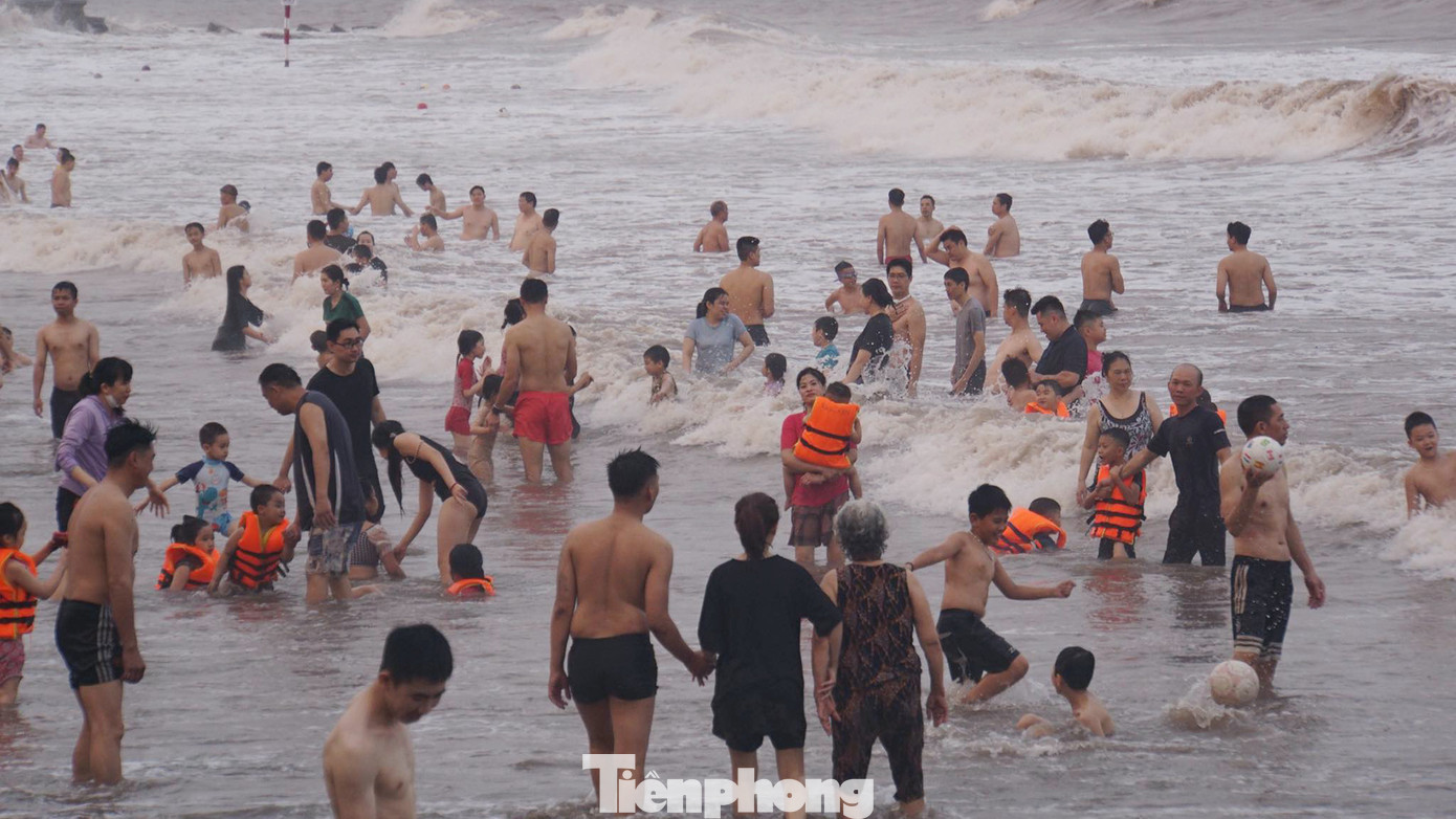 Buổi chiều, sóng mạnh, nước biển dâng cao, nhiều du khách thích thú, đùa nghịch với sóng biển.