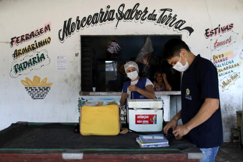 Nhân viên y tế chuẩn bị trước khi tiêm vắc xin AstraZeneca cho cộng đồng cư dân sống ven sông ở Manaus (Brazil).
