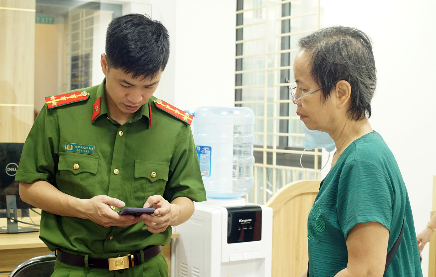 Bà Thành được Đại úy Trương Hồng Sơn hướng dẫn sử dụng ứng dụng VNeID.