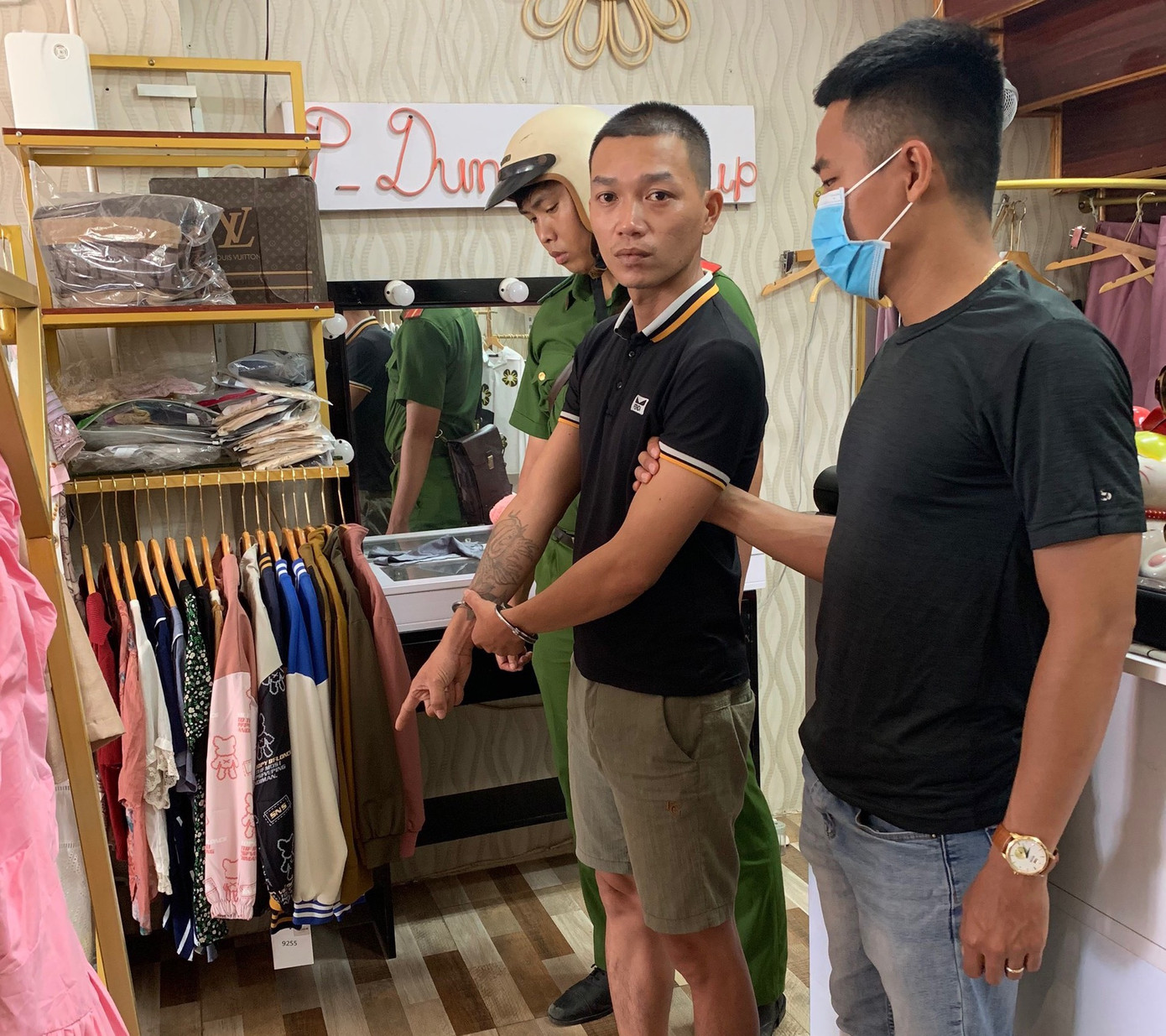 Công an dẫn giải Linh (giữa) đến cửa hàng quần áo đã thực hiện vụ cướp. Ảnh CACC.