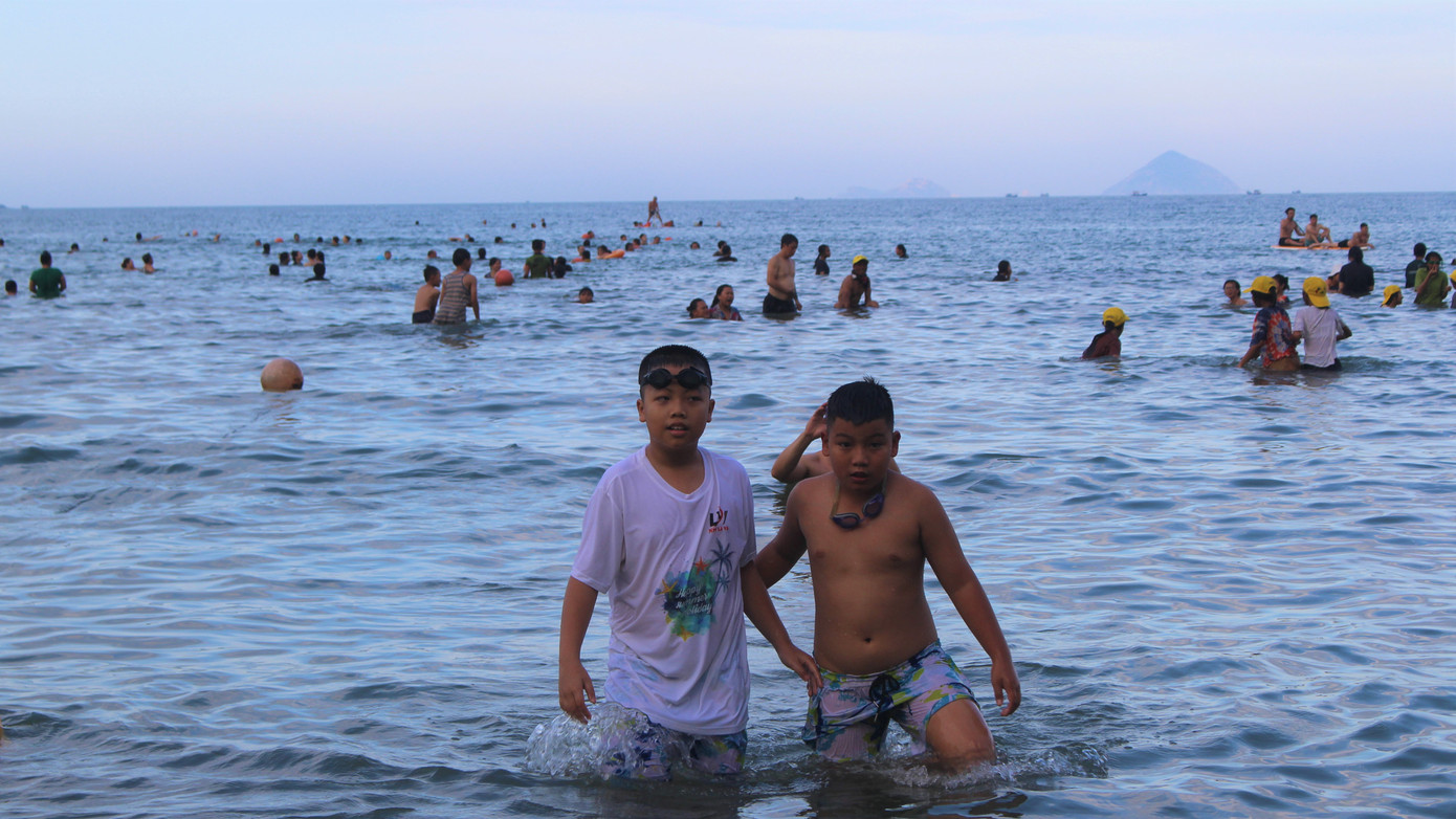 Sau 5h chiều, người dân xuống biển Nha Trang hòa mình vào làn nước mát ngày càng đông.