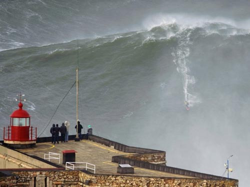 Trong khi đó, vận động viên lướt sóng chuyên nghiệp Garrett McNamara tận dụng hẻm núi ngoài khơi Nazare (Bồ Đào Nha) - được mệnh danh máy tạo sóng lớn nhất thế giới - để có cơ hội vượt qua ngọn sóng cao khoảng 30 m. Kỷ lục vượt sóng trước đó cũng thuộc về McNamara với 24 m vào ngày 1-11-2011, cũng tại Nazare. Ảnh: REUTERS/To Mane
