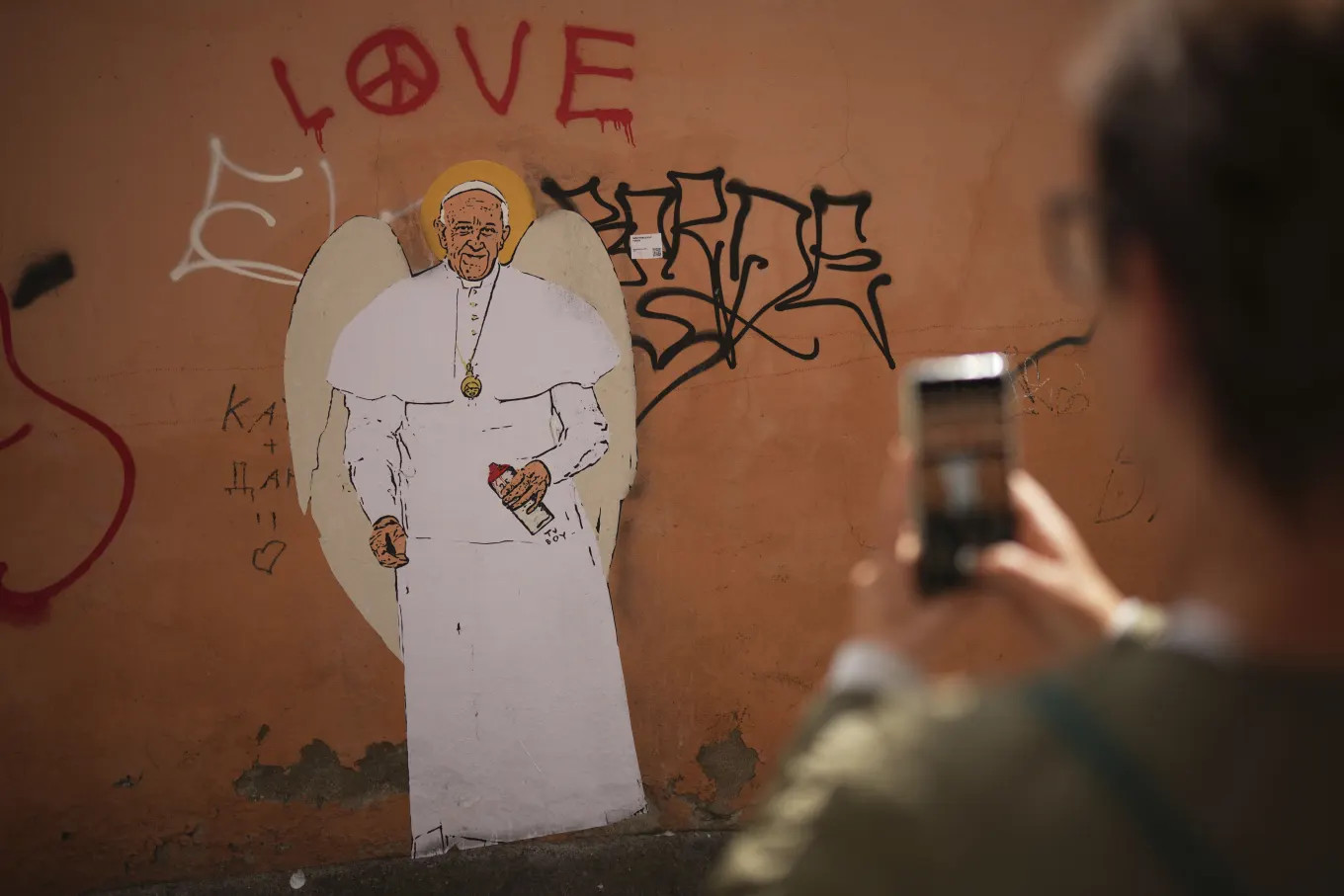 Một người chụp ảnh bức tranh tường graffiti của Giáo hoàng Francis ở Vatican. Ảnh: AP.