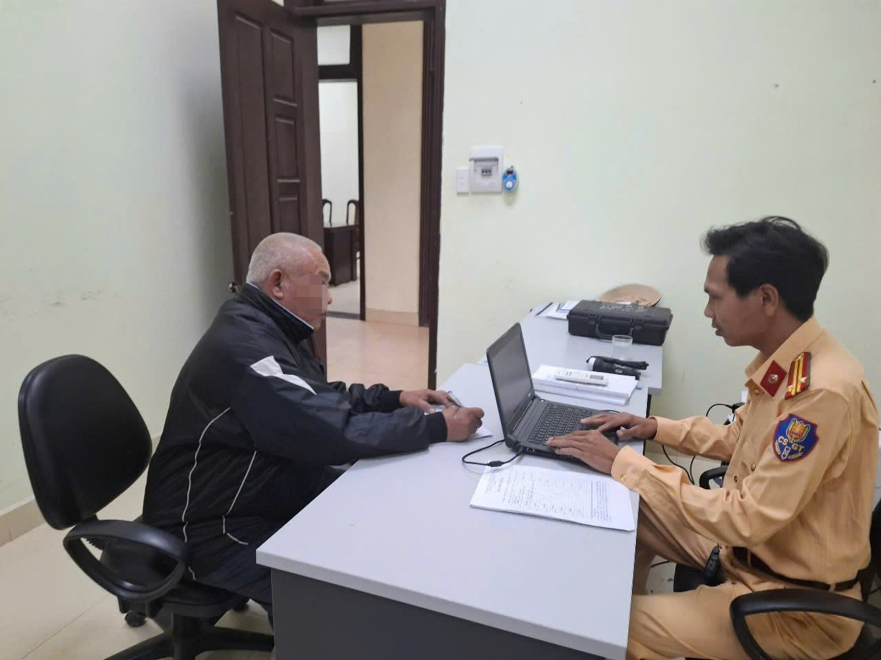 Cảnh sát giao thông lập biên bản xử phạt tài xế ô tô có hành vi cố tình vượt qua đường sắt khi tàu sắp đến. Ảnh: VNR