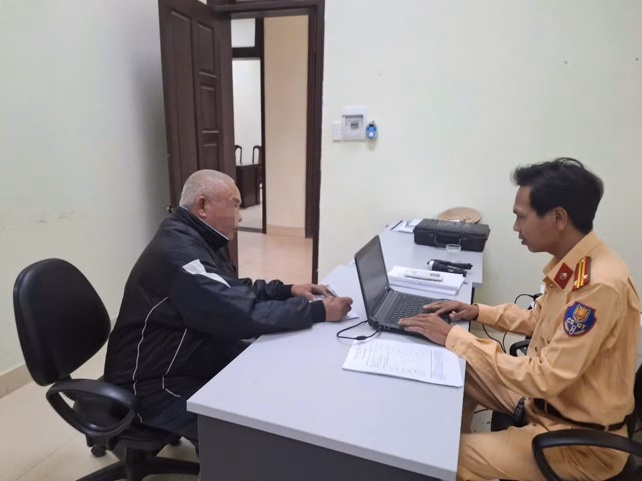 Cảnh sát giao thông lập biên bản xử phạt tài xế ô tô có hành vi cố tình vượt qua đường sắt khi tàu sắp đến. Ảnh: VNR
