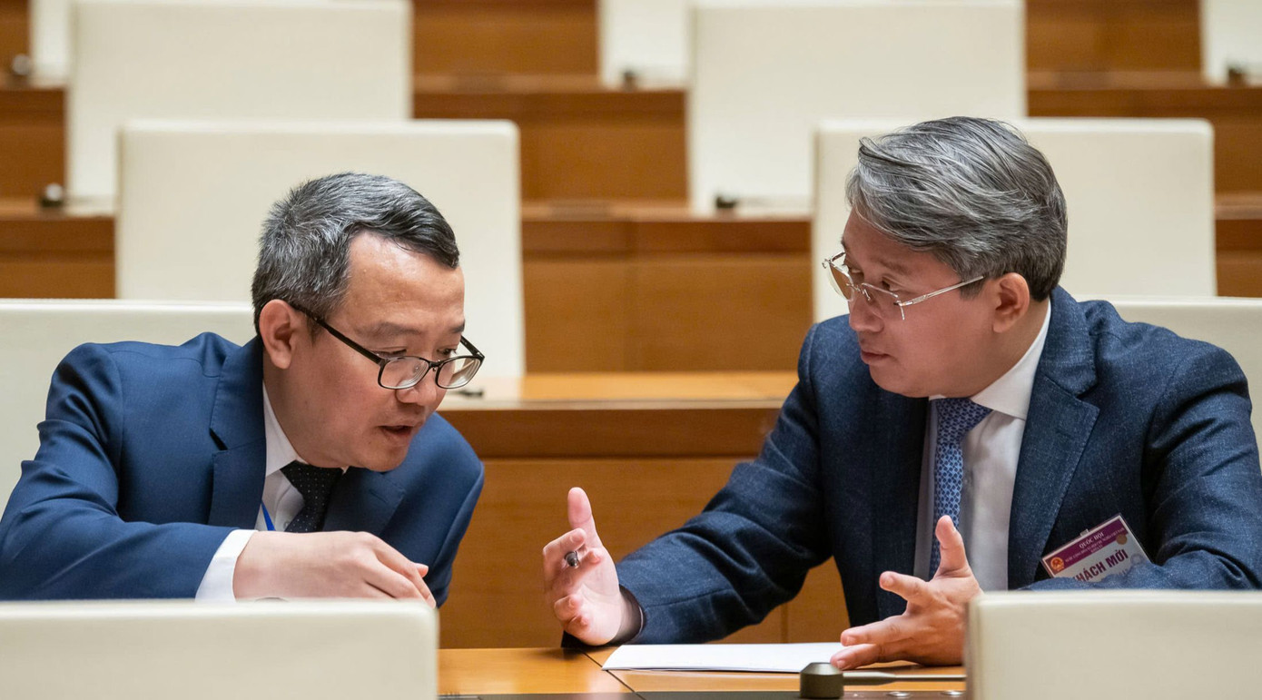 Bộ trưởng Bộ Tư pháp Nguyễn Hải Ninh (phải) trao đổi với đại biểu tại một kỳ họp Quốc hội khóa XV.