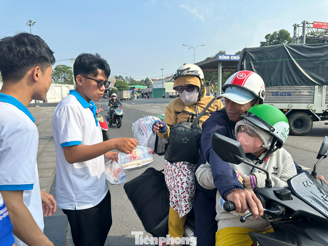 Một gia đình về quê bằng xe máy được đoàn viên thanh niên phát nước uống, đồ ăn.