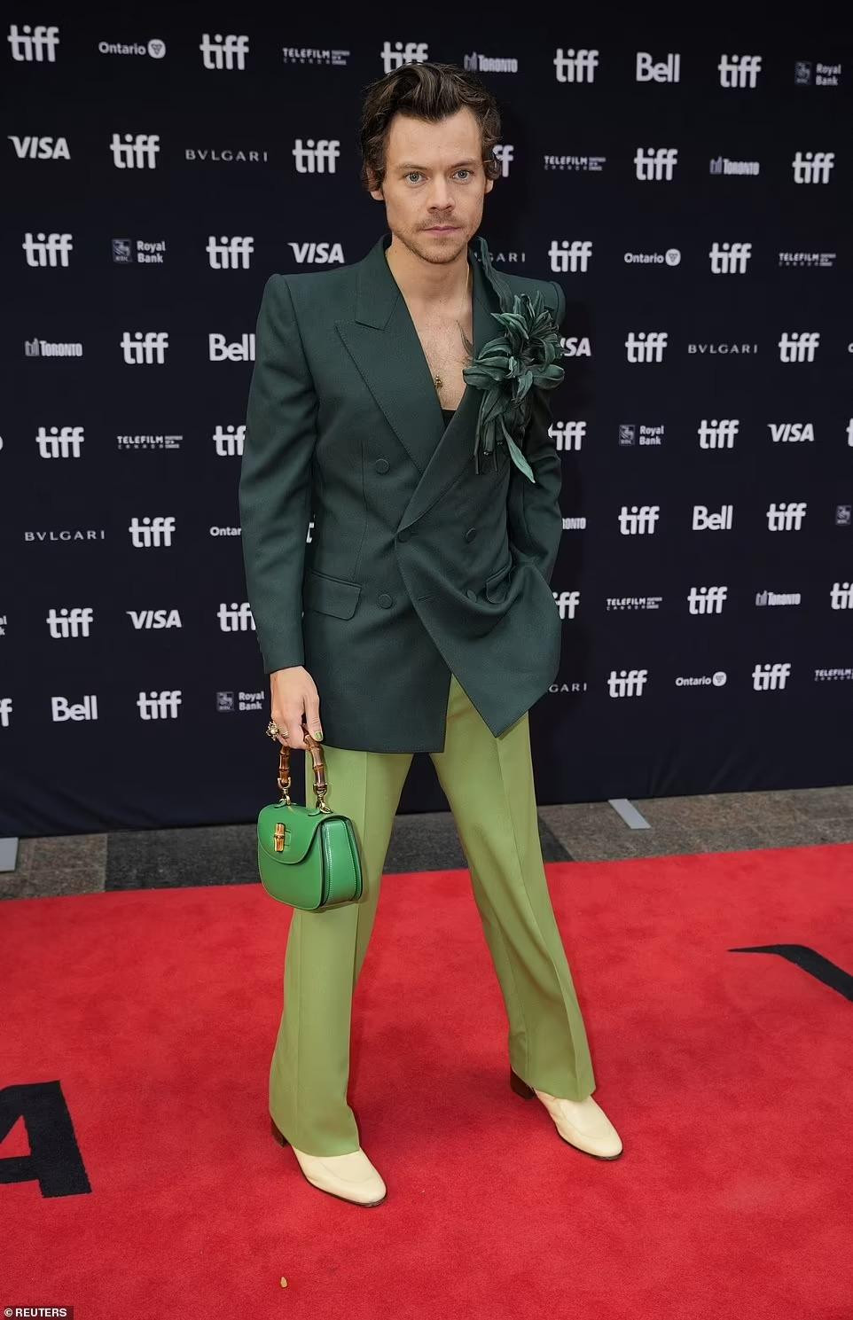 Harry diện bộ vest Gucci màu xanh lá cây và giày màu kem, kèm theo túi xách &quot;ton-sur-ton&quot;. Những năm gần đây, cựu thành viên nhóm One Direction theo đuổi phong cách phi giới tính. Một số lần xuất hiện của anh còn nữ tính đến mức nhiều người đặt nghi vấn về giới tính thật của tình cũ Taylor Swift.