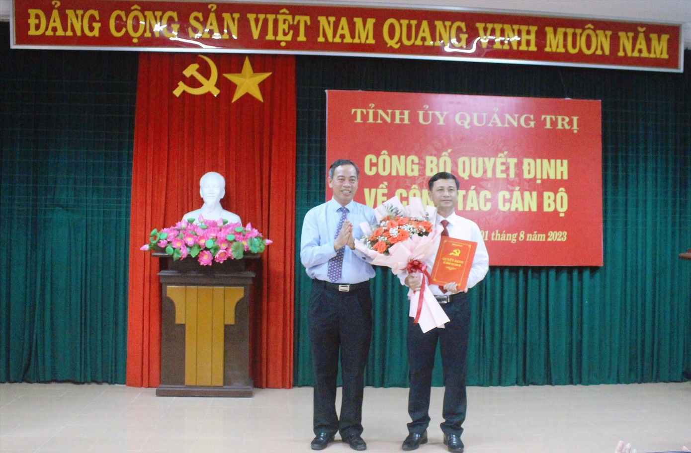 Phó Bí thư Thường trực Tỉnh ủy, Chủ tịch HĐND tỉnh Quảng Trị Nguyễn Đăng Quang (trái) trao quyết định và tặng hoa ông Trần Bình Thuận.