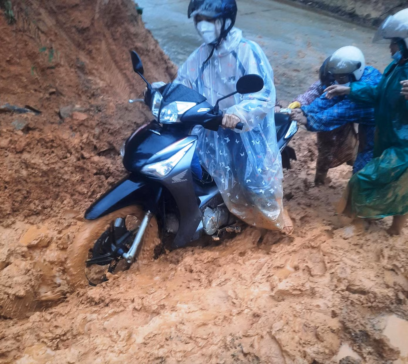 Các cô giáo Trường Mầm non An Vinh đẩy xe máy qua đoạn trường sạt lở ngập bùn đất. Ảnh: Đinh Nê
