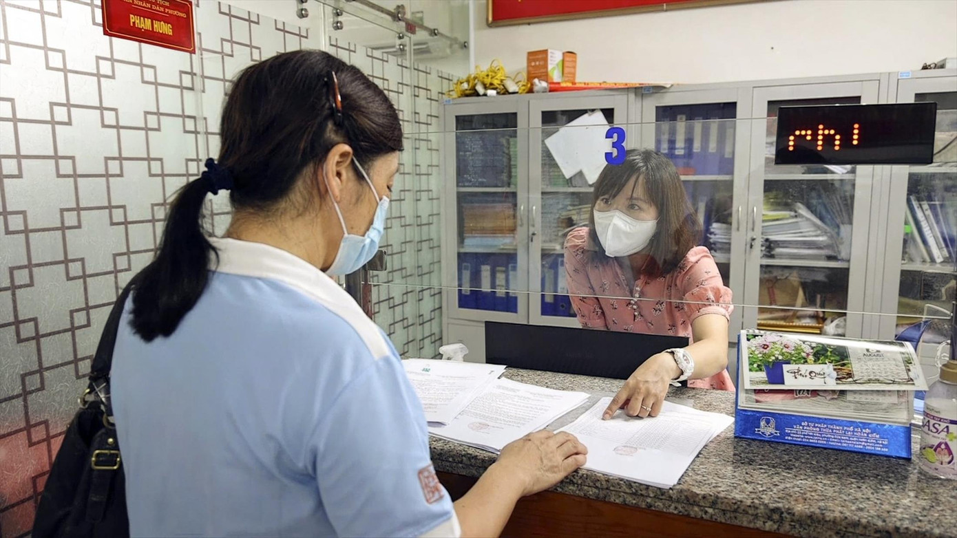 Cán bộ phường Trần Hưng Đạo (Hoàn Kiếm) tiếp dân, giải quyết thủ tục cấp giấy đi đường trong đợt giãn cách xã hội vừa qua. Ảnh: HOÀNG MẠNH THẮNG