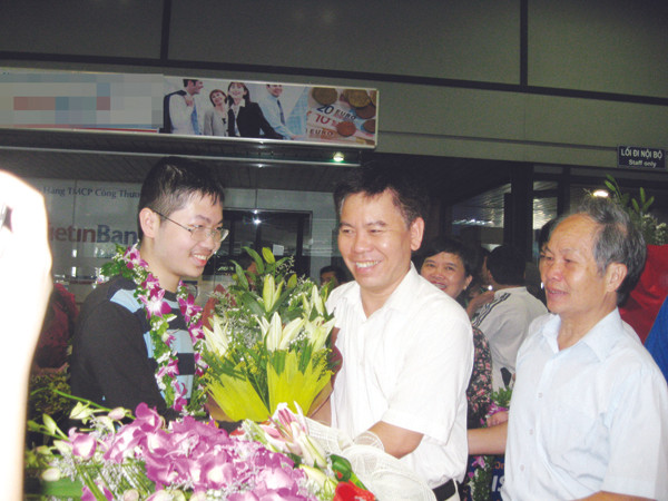 Thày Nguyễn Đức Hoàng chúc mừng Đậu Hải Đăng (trái) tại sân bay Nội Bài. Người ngoài cùng bên phải là bố của Đăng Ảnh: Quý Hiên