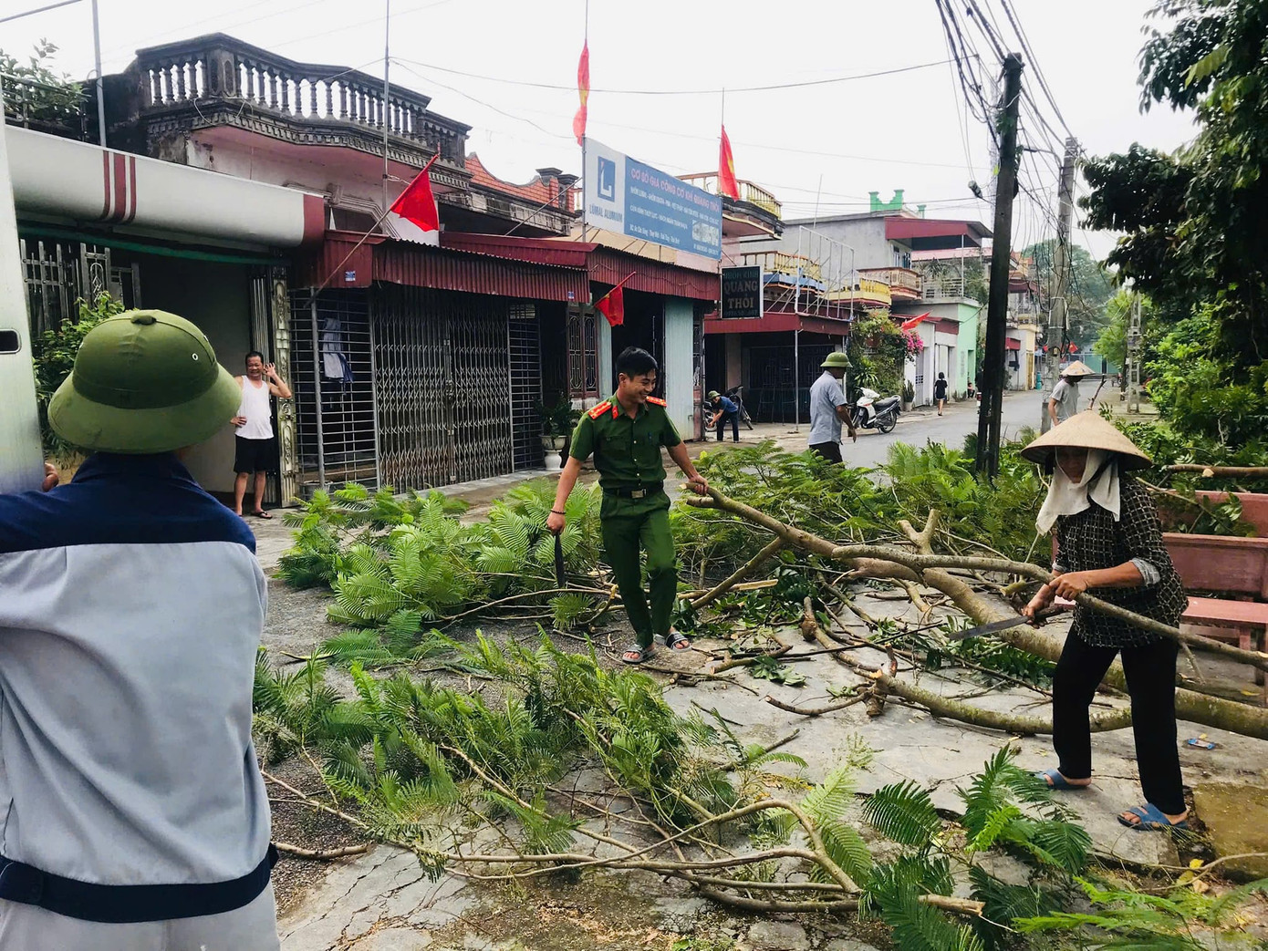 Chiến sĩ Công an nhân dân cùng người dân địa phương dọn dẹp, tỉa cành cây để đảm bảo an toàn khi bão đến. Ảnh: Tuổi trẻ Công an Thái Bình