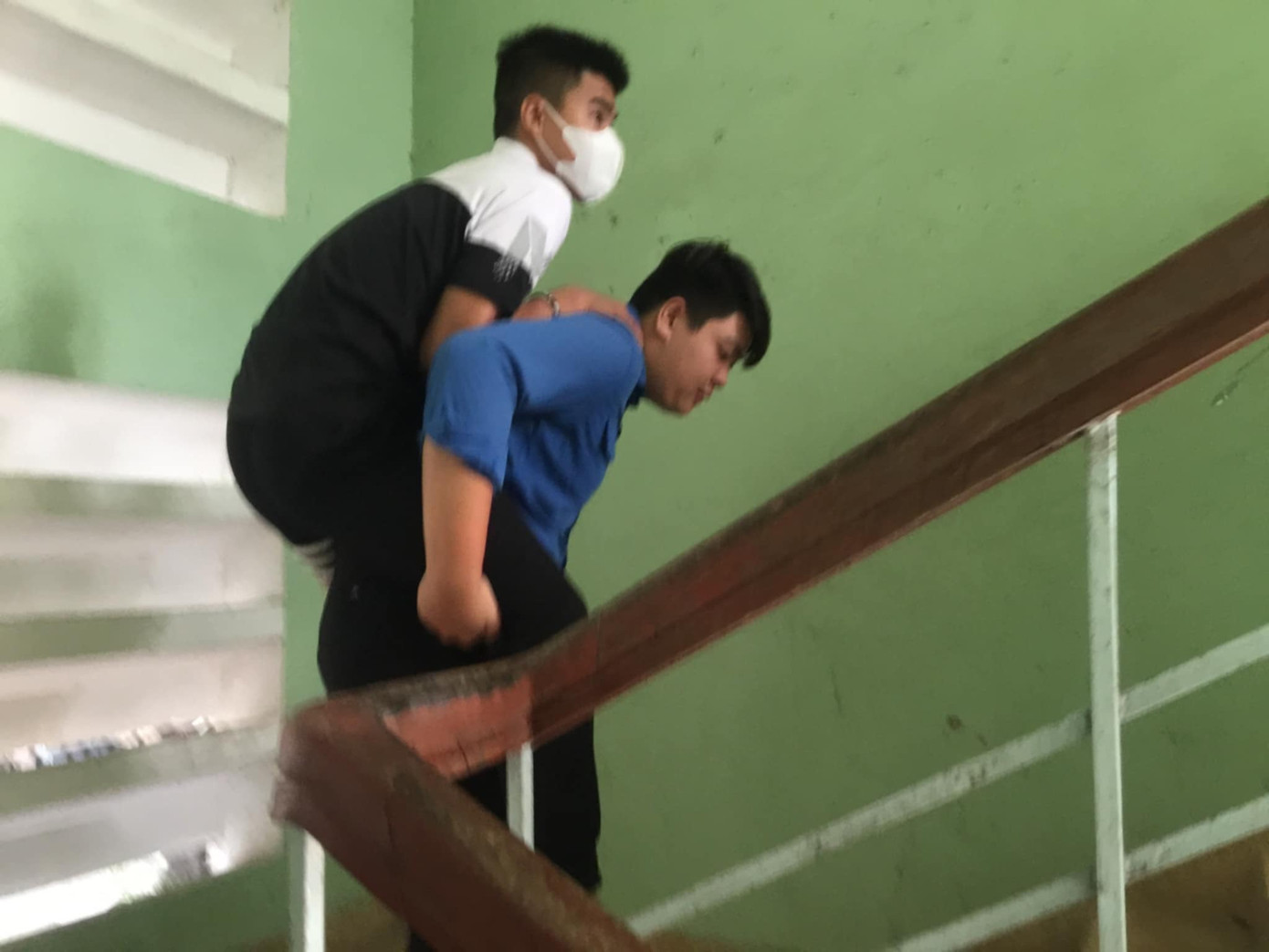 Tình nguyện viên cõng bạn Chiến Thắng đến phòng thi ở tầng 2 để kịp giờ thi. Ảnh: Nguyễn Linh/báo Lao Động.