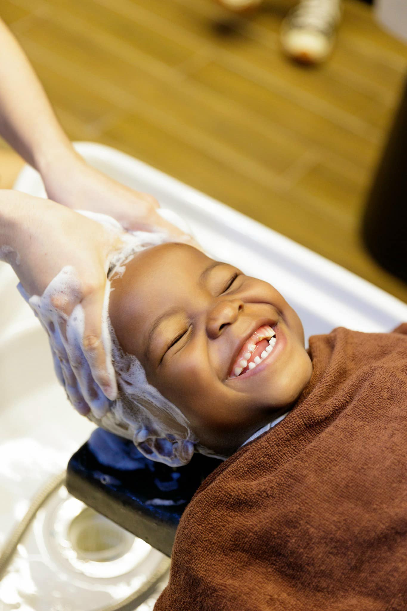 Cậu bé vui khoái chí khi được các chú đưa đi cắt tóc, gội đầu.