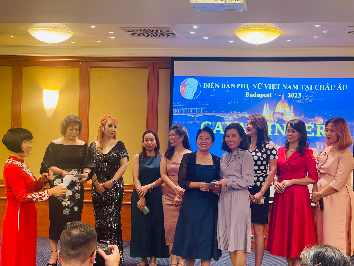 Bà Trịnh Thị Mùi (thứ sáu từ trái sang) trao số tiền hỗ trợ "Mẹ đỡ đầu" tặng Phó Chủ tịch Liên hiệp Phụ nữ Việt Nam Nguyễn Thị Minh Hương cùng các mẹ đỡ đầu người Việt tại châu Âu ngay tại diễn đàn (Ảnh: L.A) Bà Trịnh Thị Mùi (thứ sáu từ trái sang) trao số tiền hỗ trợ "Mẹ đỡ đầu" tặng Phó Chủ tịch Liên hiệp Phụ nữ Việt Nam Nguyễn Thị Minh Hương cùng các mẹ đỡ đầu người Việt tại châu Âu ngay tại diễn đàn (Ảnh: L.A)