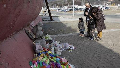 Một gia đình đang cầu nguyện cho các nạn nhân thảm họa sóng thần năm 2011 tại cảng Kesennuma. Một gia đình đang cầu nguyện cho các nạn nhân thảm họa sóng thần năm 2011 tại cảng Kesennuma