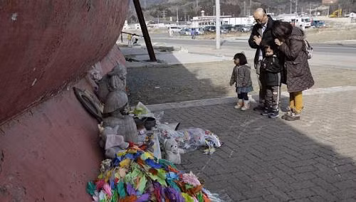 Một gia đình đang cầu nguyện cho các nạn nhân thảm họa sóng thần năm 2011 tại cảng Kesennuma. Một gia đình đang cầu nguyện cho các nạn nhân thảm họa sóng thần năm 2011 tại cảng Kesennuma