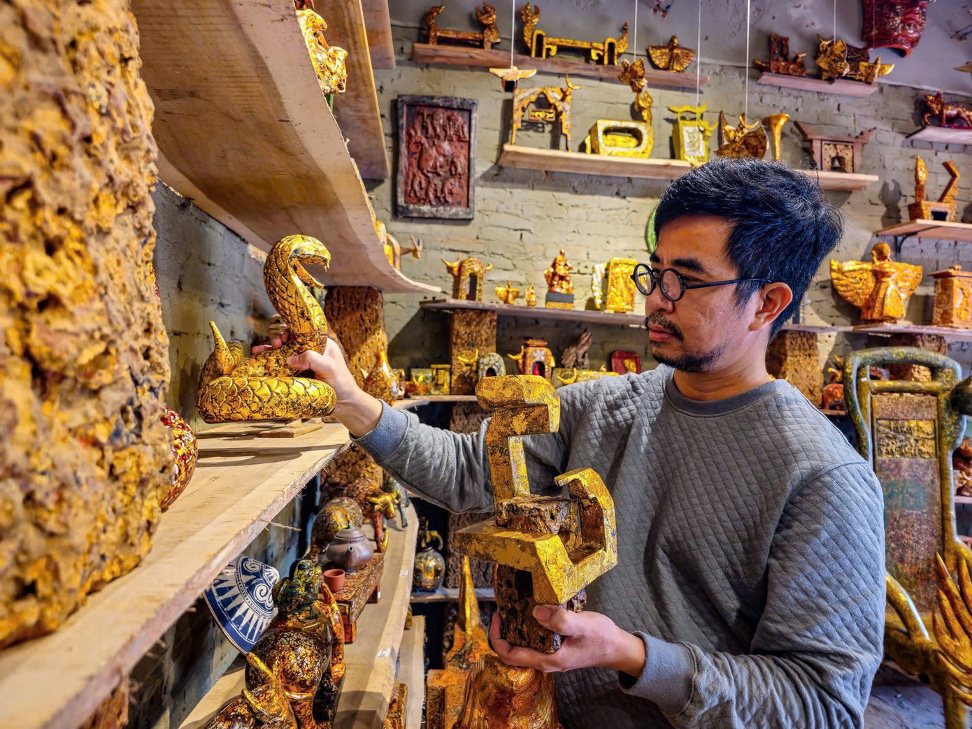 Nghệ nhân Nguyễn Tấn Phát bên bộ sưu tập Rắn sơn mài trên đá ong.