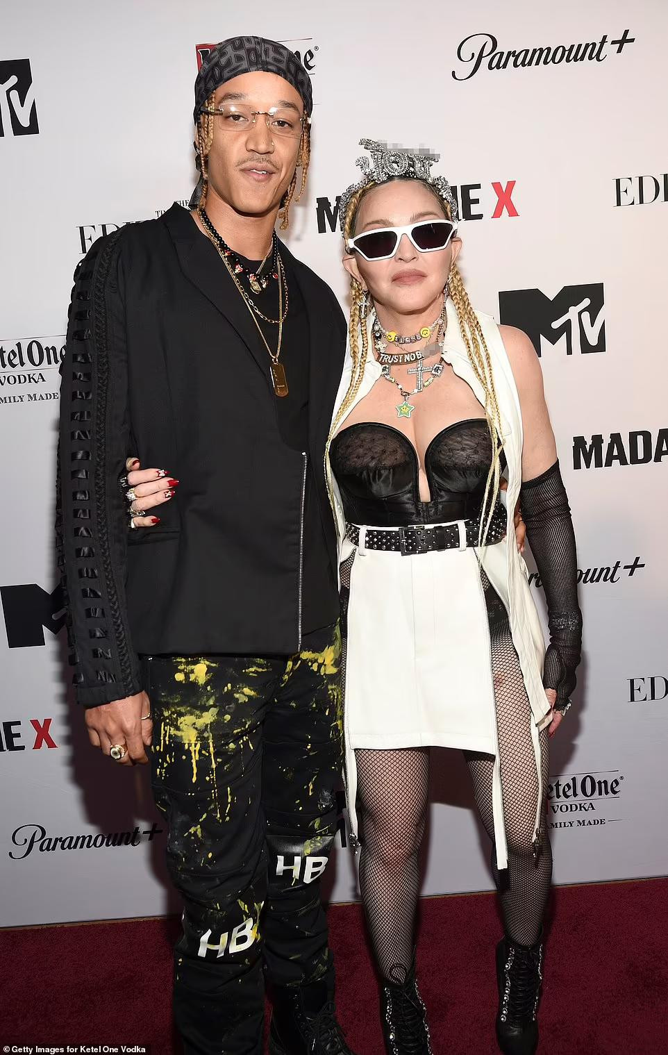 "Nữ hoàng nhạc Pop" ở tuổi U70 vẫn nổi loạn với phong cách thời trang táo bạo, khoe vòng một nóng bỏng với áo lót ngực màu đen, quần tất xuyên thấu với chân váy xẻ cao lộ rõ nội y bên trong. Trong khi đó, bạn trai kém 36 tuổi của Madonna mặc rất phong cách và đậm chất nghệ sĩ.