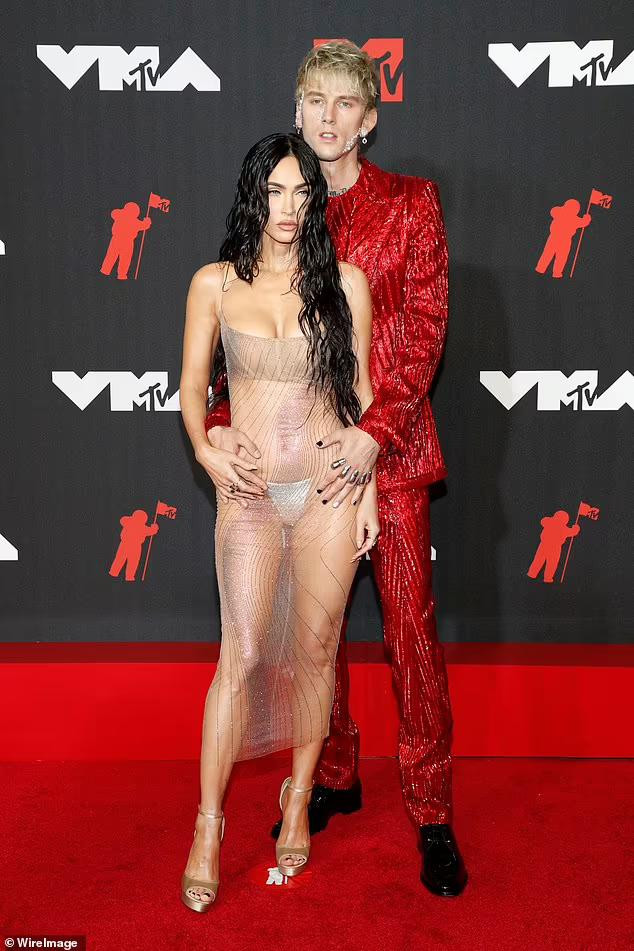 Trong khi Megan Fox hở bạo nhất thảm đỏ sự kiện với bộ váy xuyên thấu mặc như không của Mugler thì bạn trai kém 4 tuổi của cô - rapper Machine Gun Kelly - lại kín bưng trong bộ vest đỏ rực của Dolce &amp; Gabbana.