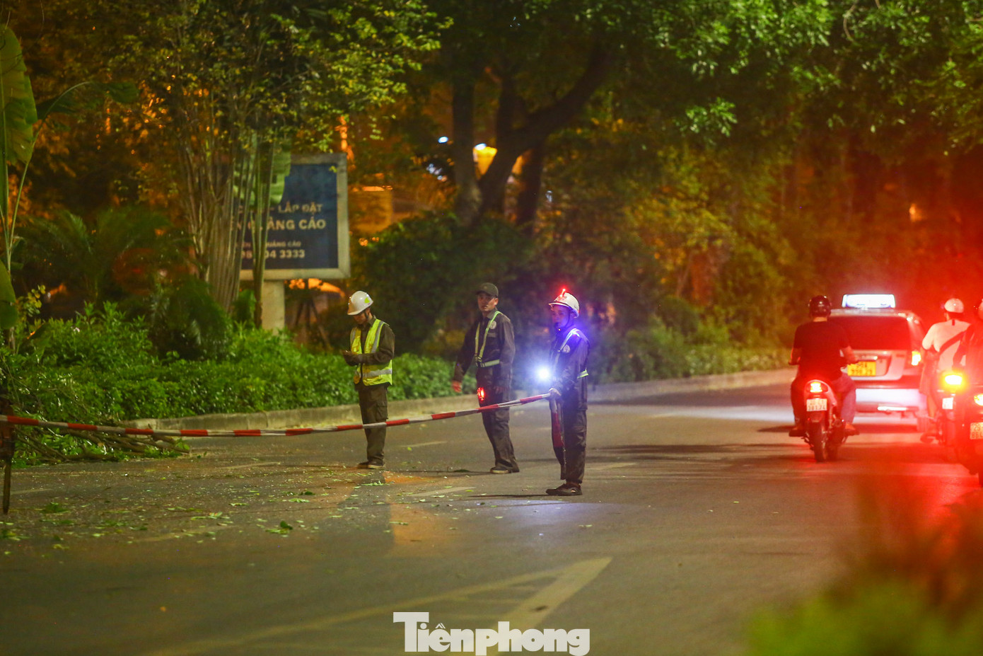 Công nhân cây xanh hướng dẫn các phương tiện đi qua nhằm bảo đảm an toàn.