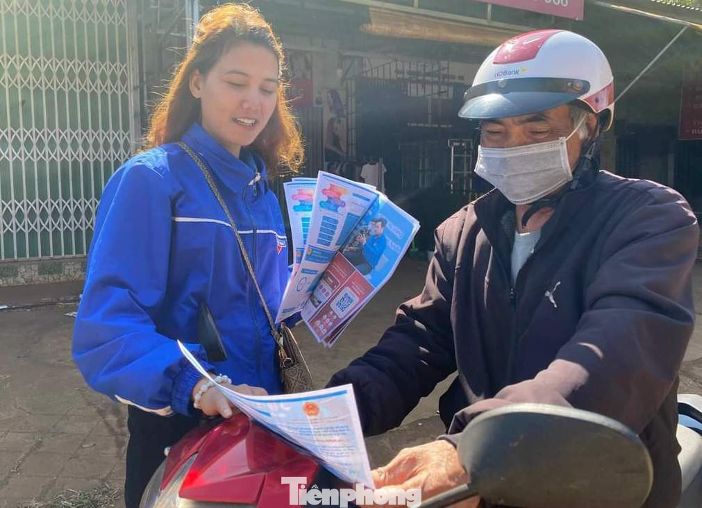 Tình nguyện viên phát tờ rơi tuyên truyền về chuyển đổi số cho người dân